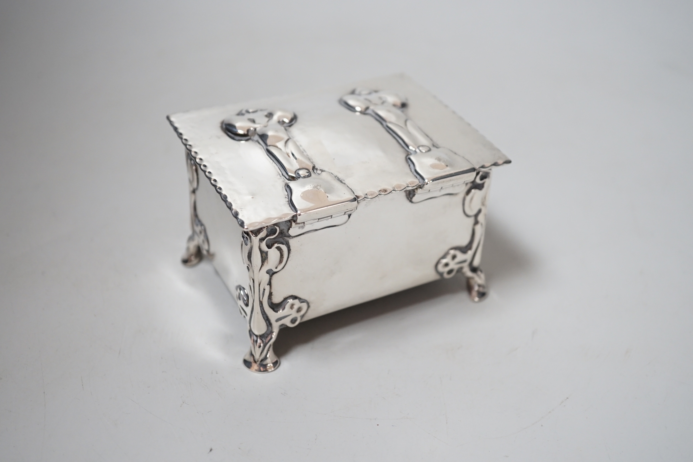 An Edwardian Arts & Crafts Kate Harris for William Hutton & Sons rectangular silver box, of lidded casket form, with relief cast foliate bracket feet, strap hinges and cedar lined interior, London, 1902, width 10.2cm, gr